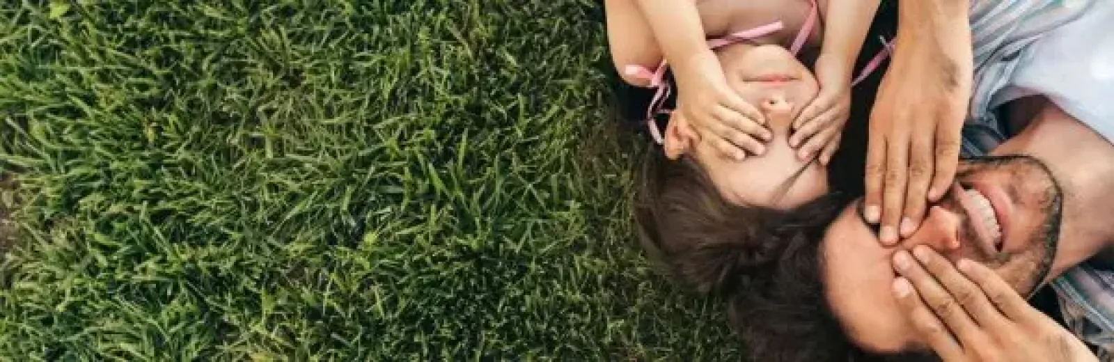 Father and daughter lying in the grass