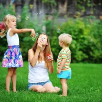Family sitting in green summer grass blowing bubbles