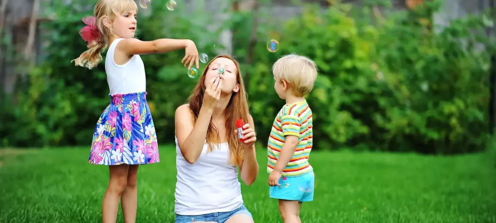 Family sitting in green summer grass blowing bubbles
