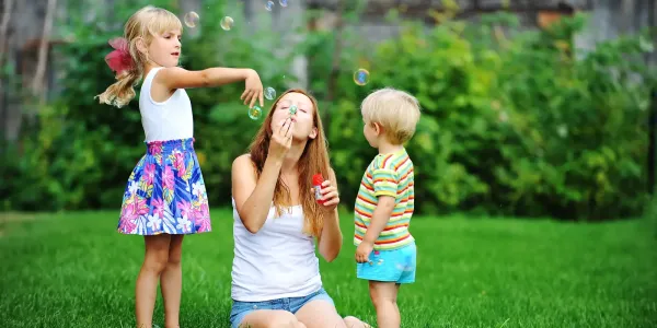 Family sitting in green summer grass blowing bubbles